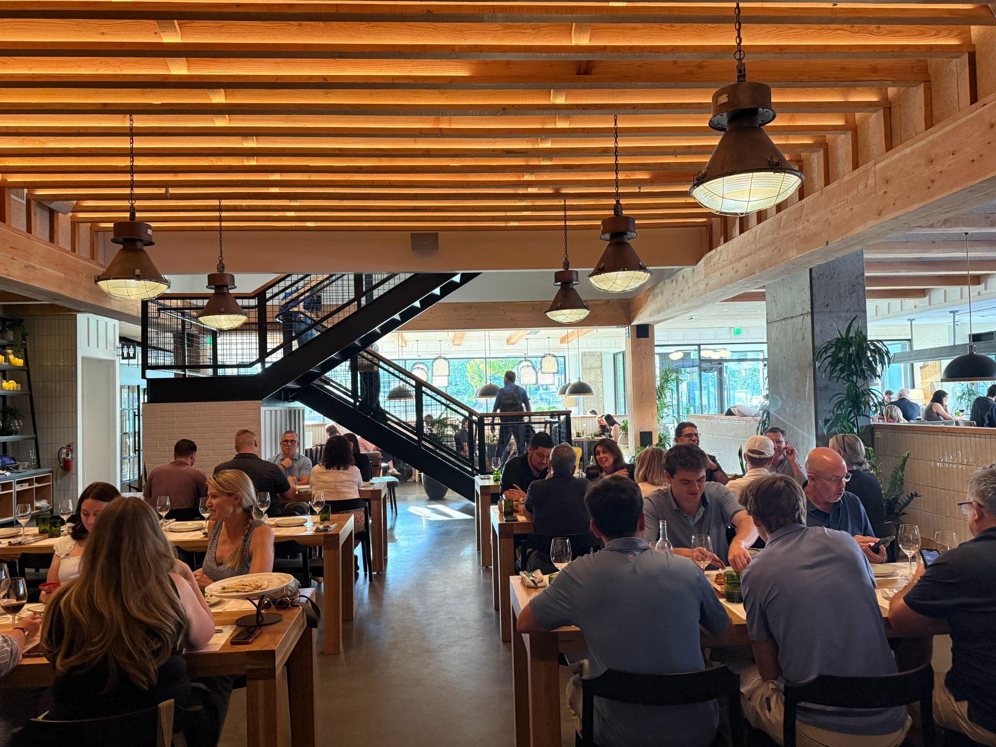 Sixty Vines dining room in North Hills Raleigh with wood-beam ceiling, pendant lights, and couples dining