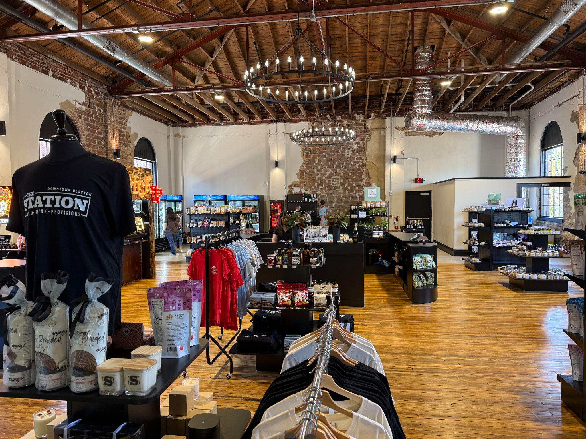 Inside The Station in Downtown Clayton — a restored historic building with exposed brick, wood floors, and a market of local goods and apparel