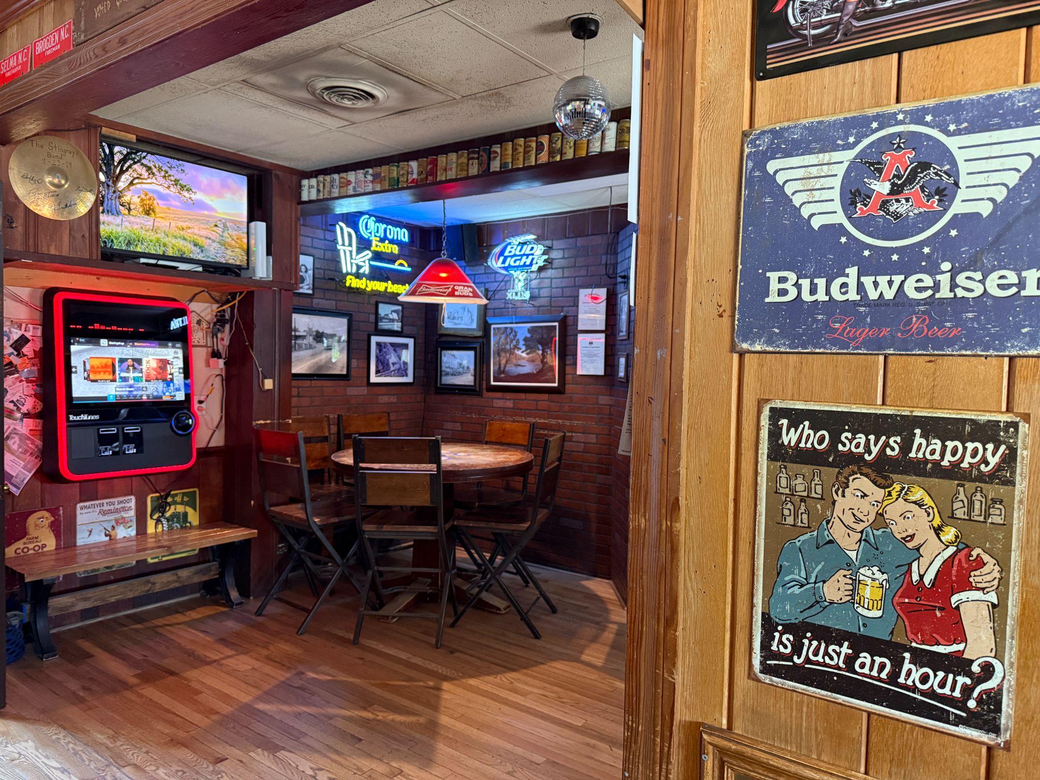 Cozy wood-paneled interior of Little Brown Jug in Smithfield with a jukebox, neon beer signs, and vintage decor