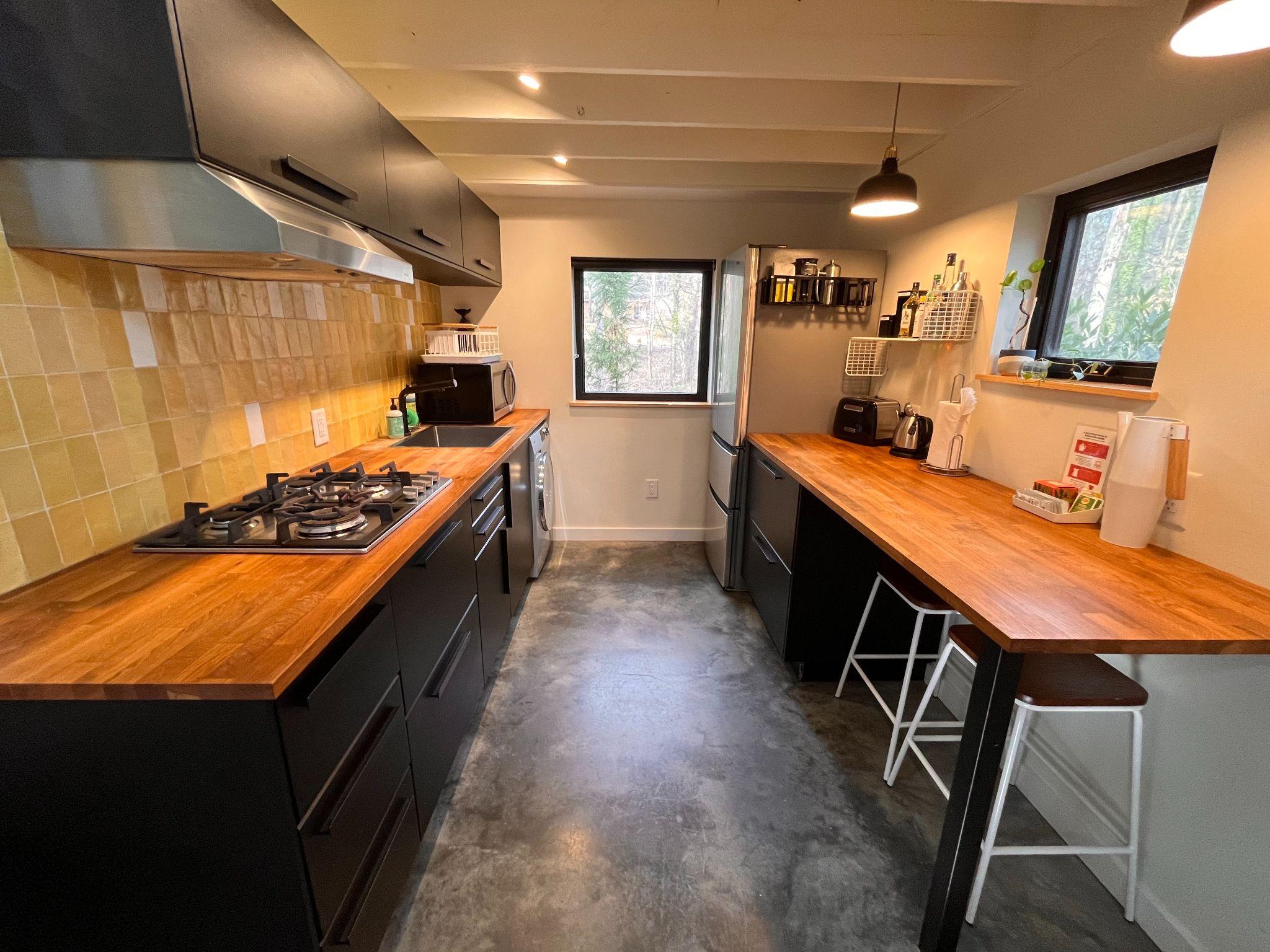 Galley kitchen in the Durham tiny house with yellow tile backsplash, butcher-block counters, and a breakfast bar