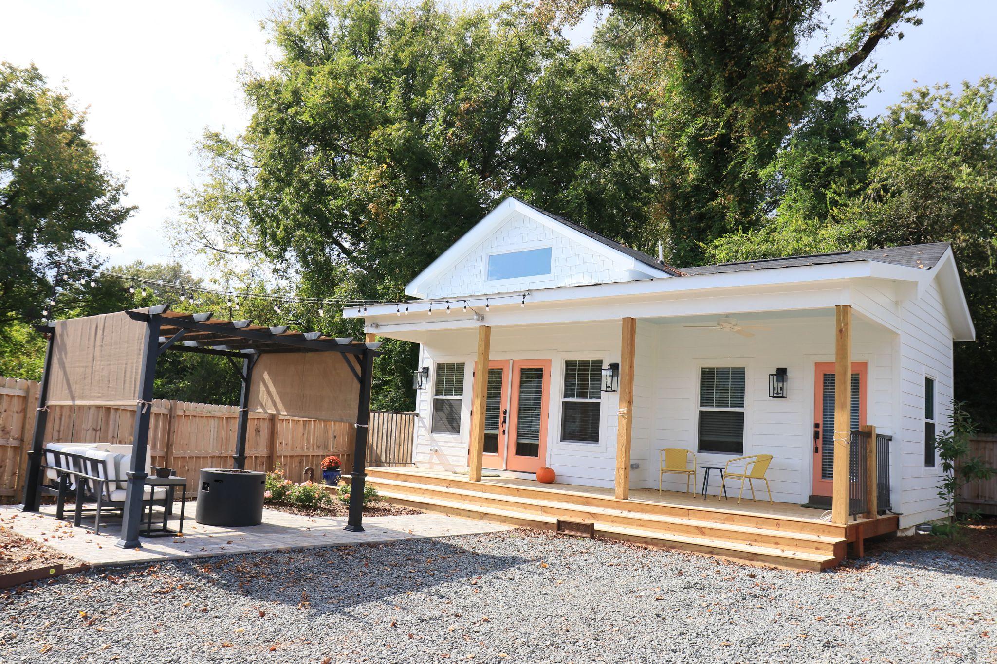 The Farmhouse at Scout, a white cottage with a covered porch and a pergola-shaded patio, in downtown Durham