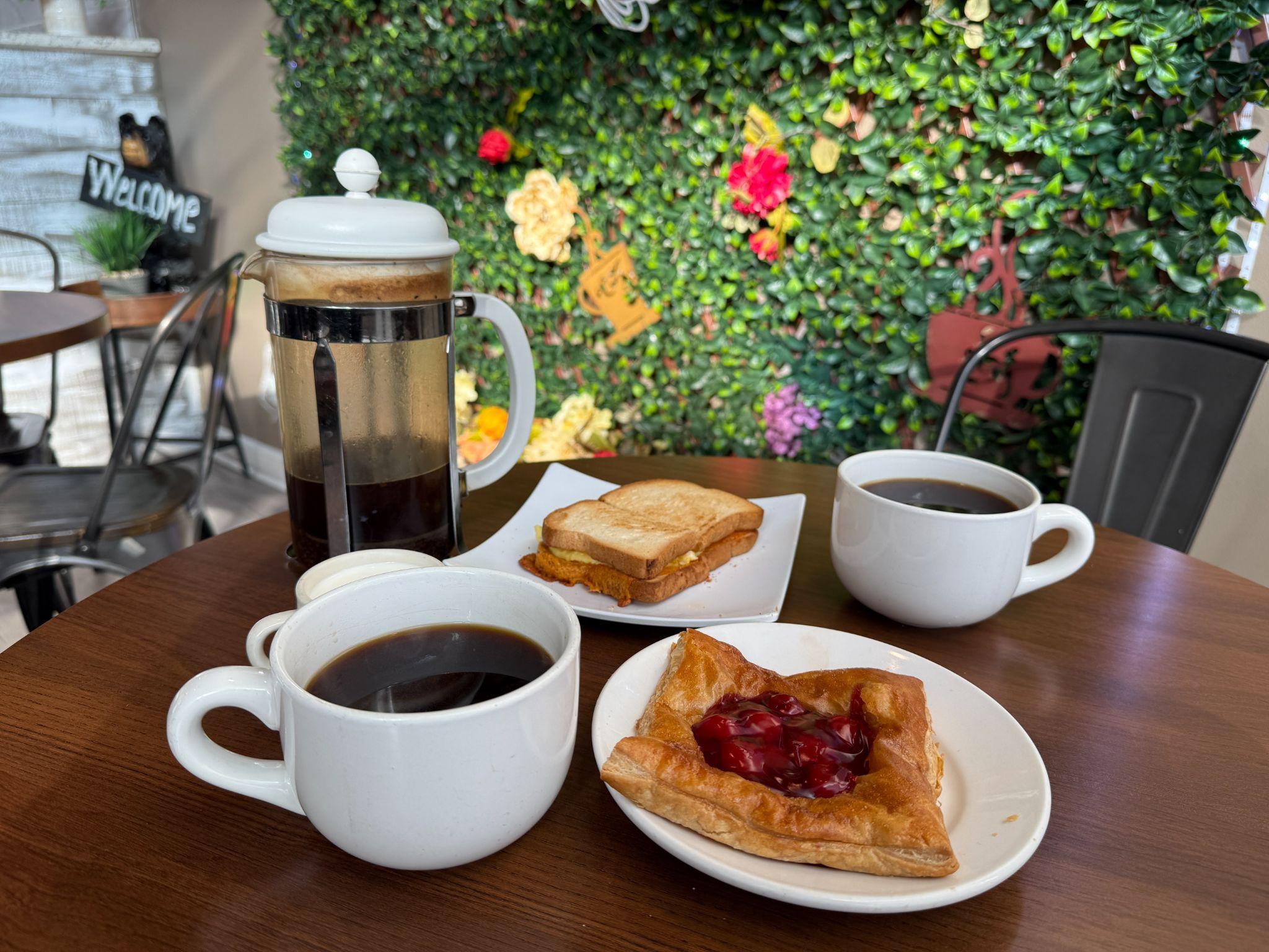 French press coffee, toast, and a cherry danish on a café table in downtown New Bern