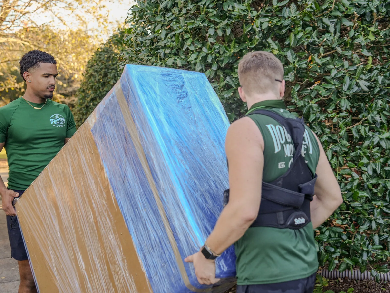 Dogwood movers carrying a professionally wrapped mattress